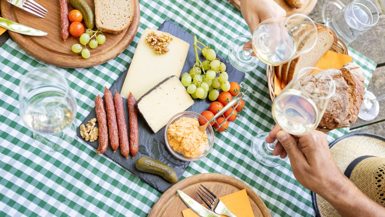 Heurigenjause, © Weinviertel Tourismus GmbH / Schwarz-König Picknick mit Käse, Wurst, Brot und Wein auf kariertem Tischtuch.