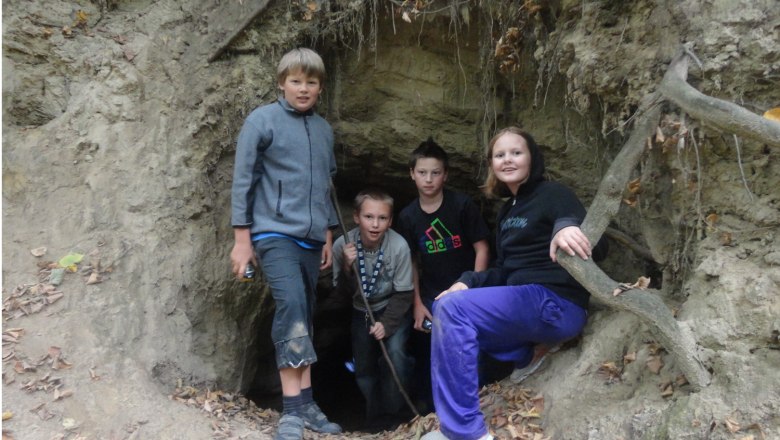 Schwedenhöhlen, © Gemeinde Harmannsdorf Vier Kinder stehen vor einem Höhleneingang in einem Wald.