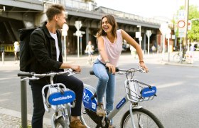Nextbike Radverleih, © pixabay Zwei Personen auf Nextbike-Fahrrädern in einer Stadt, lachend und sich unterhaltend.