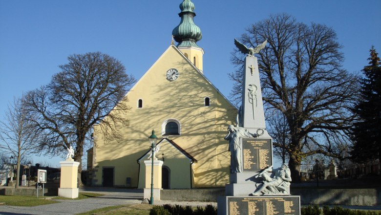 Pfarrkirche des heiligen Hippolyt mit Kriegerdenkmal im Vordergrund.